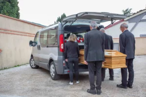 Porteurs funéraires chargeant un cercueil en bois massif dans un véhicule de transport