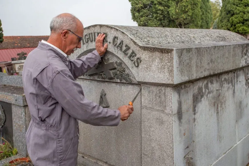 Marbreur funéraire effectuant des travaux d'entretien et d'étanchéité sur un monument en pierre