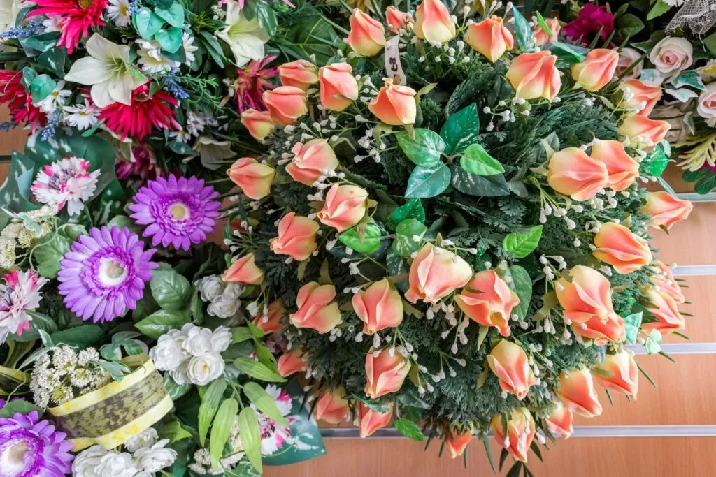 Gros plan sur une composition florale funéraire garnie de boutons de roses pêche