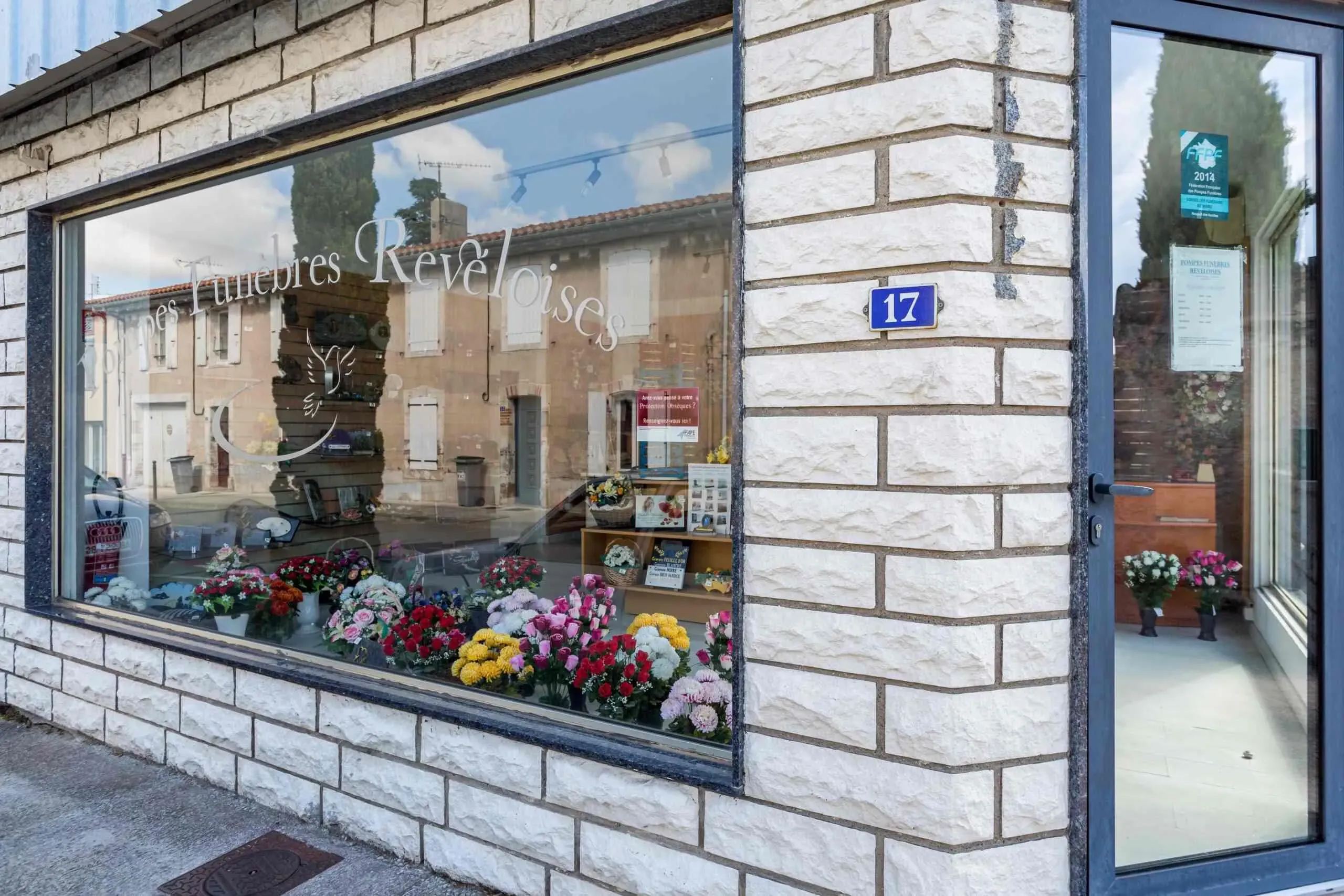 Vitrine extérieure de l'agence Pompes Funèbres Revéloises avec fleurs et ornements